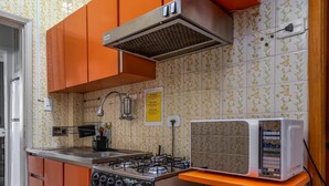 A kitchen with orange cabinets, a gas stove, a microwave, and a sink. - Style in Copacabana Near the Beach Br403 (Rio de Janeiro)