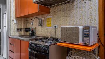 A kitchen with orange cabinets, a gas stove, a microwave, and a sink.