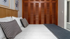 A bedroom with a wooden wardrobe, a bed with white bedding, and two patterned pillows. - Style in Copacabana Near the Beach Br403 (Rio de Janeiro)
