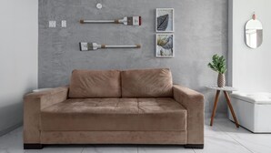 A modern living room with a beige sofa, a small round table with a potted plant, and wall-mounted art pieces. - Style in Copacabana Near the Beach Br403 (Rio de Janeiro)