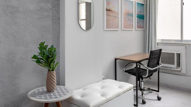 A modern living room with a white sofa, a round table with a plant, and a black office chair. - Style in Copacabana Near the Beach Br403 (Rio de Janeiro)