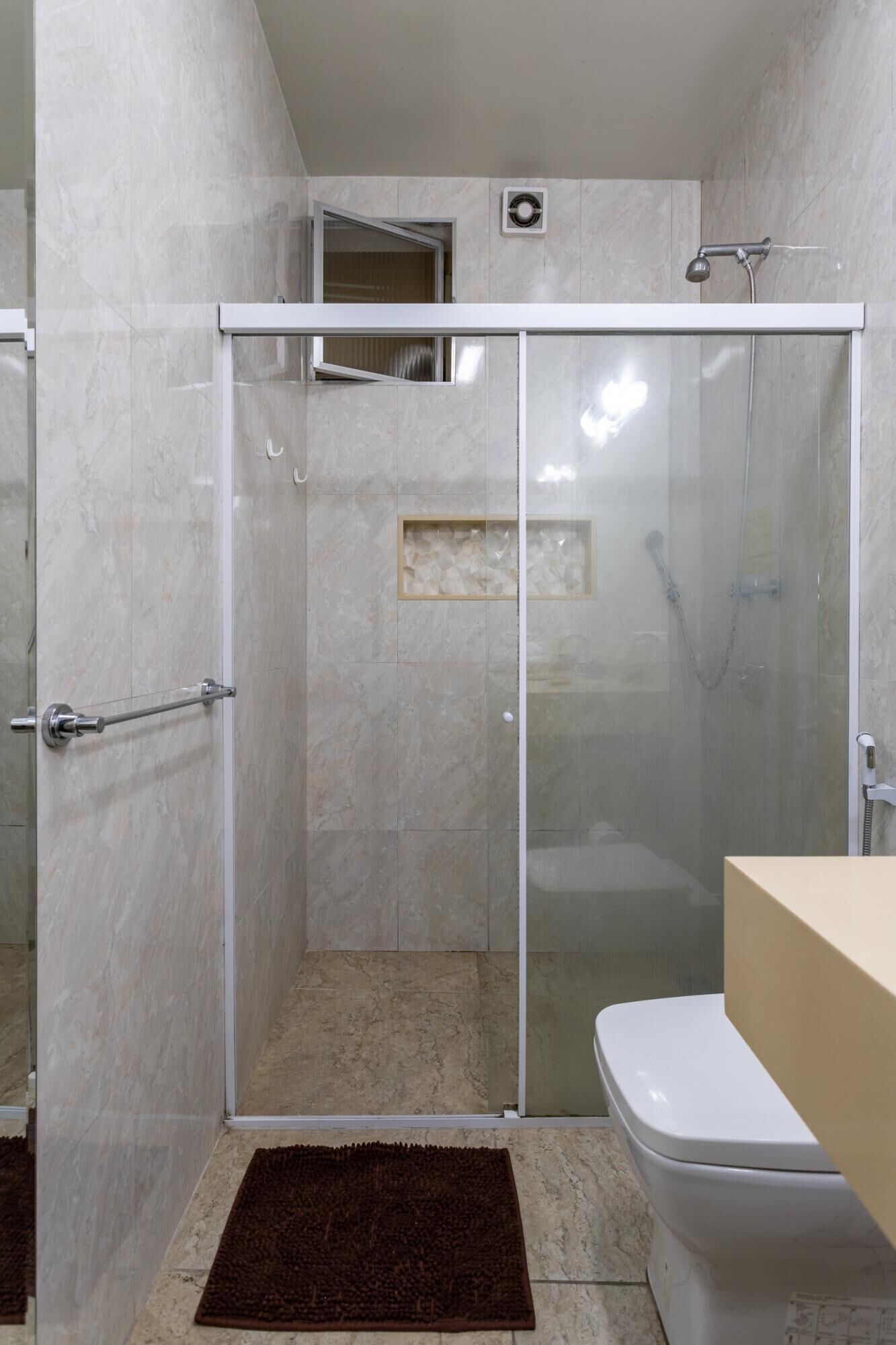 A bathroom with a glass-enclosed shower, a toilet, and a sink.