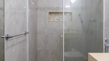 A bathroom with a glass-enclosed shower, a toilet, and a sink.