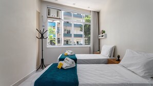A hotel room with two beds, a large window, a coat rack, and a small plant on the nightstand. - 3 Minutes From Copacabana Beach Df219 (Rio de Janeiro)