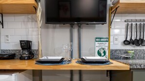 Una cucina con TV, microonde, macchina del caffè e sgabelli gialli.