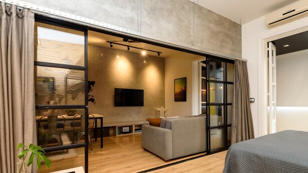 A modern hotel room with a sliding glass door leading to a balcony, a grey sofa, a flat-screen TV, and a bed with a grey quilt. - 5 Minutes From Copacabana Beach Nsc902 (Rio de Janeiro)