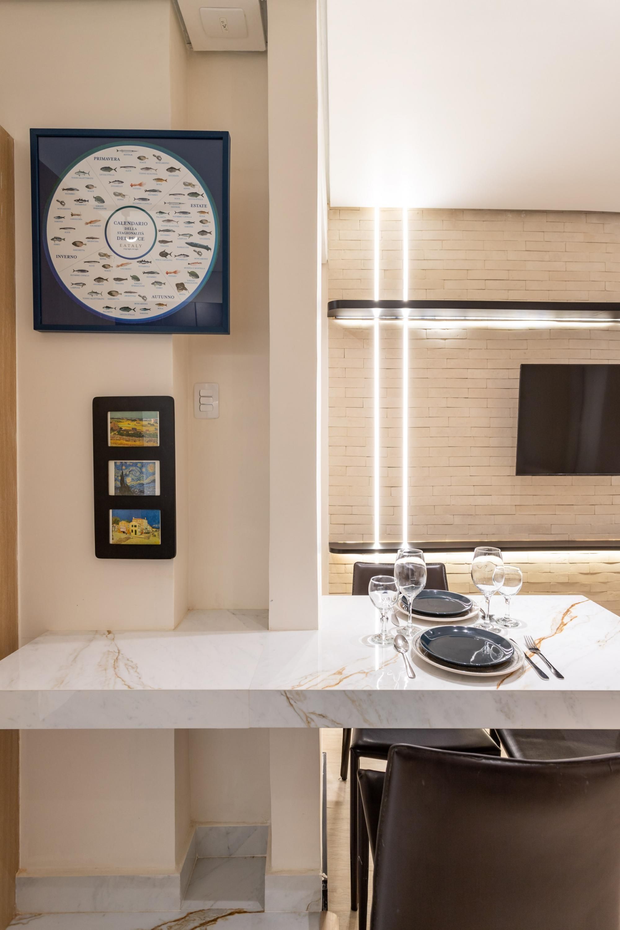 A dining area with a marble table, chairs, and a framed seafood calendar on the wall.