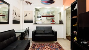 Uma sala de estar moderna com um sofá preto, um tapete estampado e uma pequena decoração de veleiro.