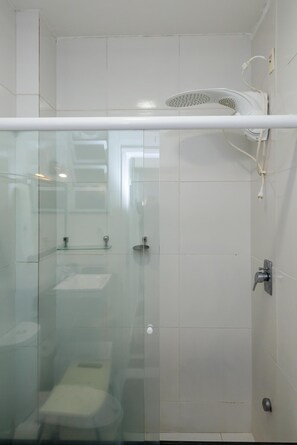 Ein modernes Badezimmer mit einer Duschkabine, einem weißen Waschbecken und einer Toilette.