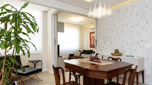 A dining area with a wooden table, chairs, a potted plant, and a decorative wall. - 2 Minutes From Copacabana Beach Nsc601 (Rio de Janeiro)