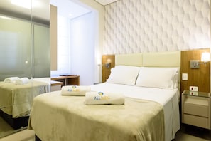 Ein Hotelzimmer mit Bett, Nachttisch, Spiegel und Wand mit geometrischem Muster.