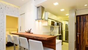 A modern kitchen with a central island, white bar stools, stainless steel appliances, and a wooden door. - 2 Minutes From Copacabana Beach Nsc601 (Rio de Janeiro)