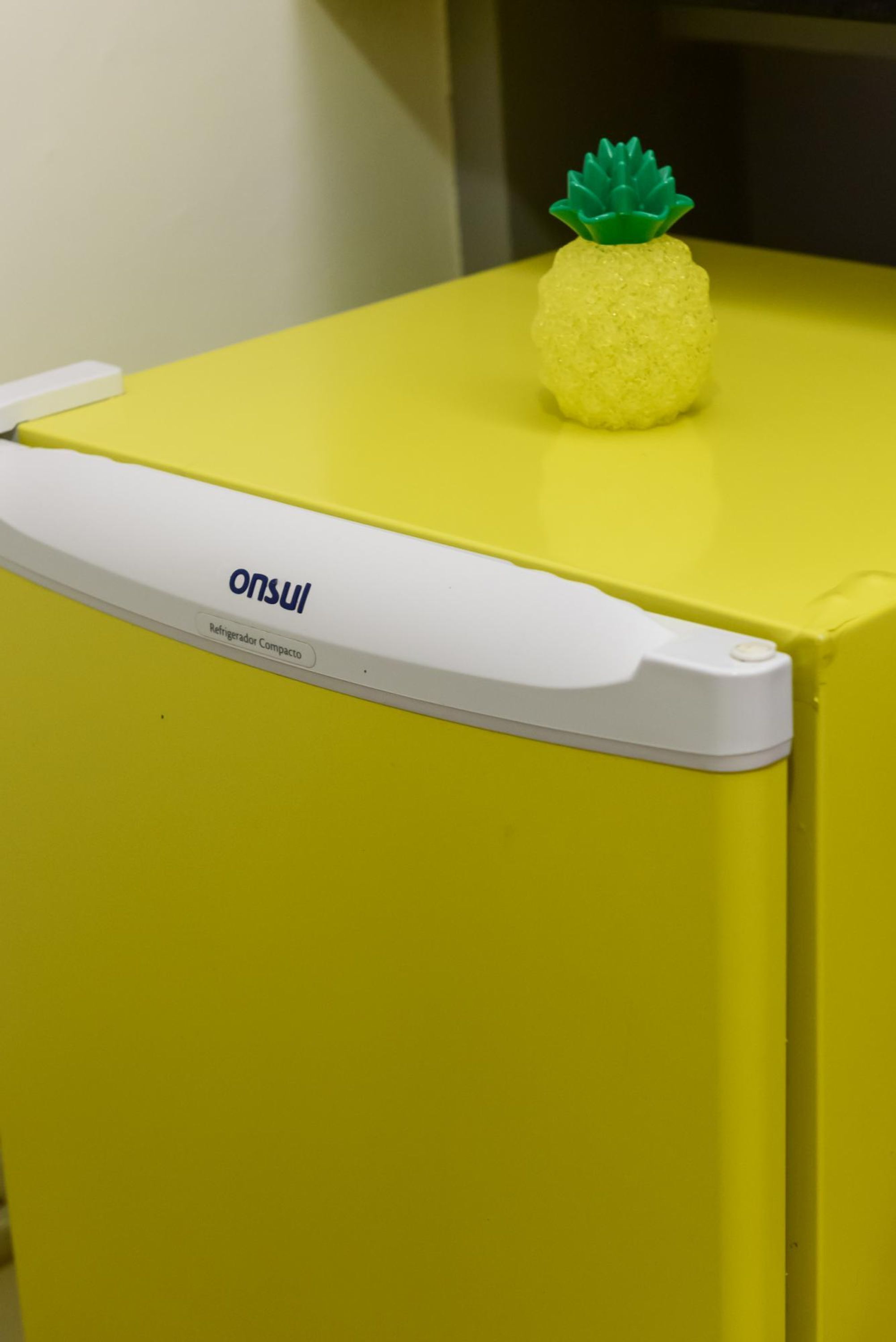 Un refrigerador compacto con exterior amarillo y panel frontal blanco etiquetado como 'onsul Refrigerator Compacto'.