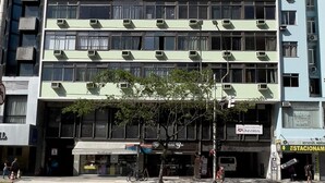 Ein mehrstöckiges Gebäude mit vielen Klimaanlagen, einem sichtbaren Ladenlokal im Erdgeschoss und blauem Himmel.