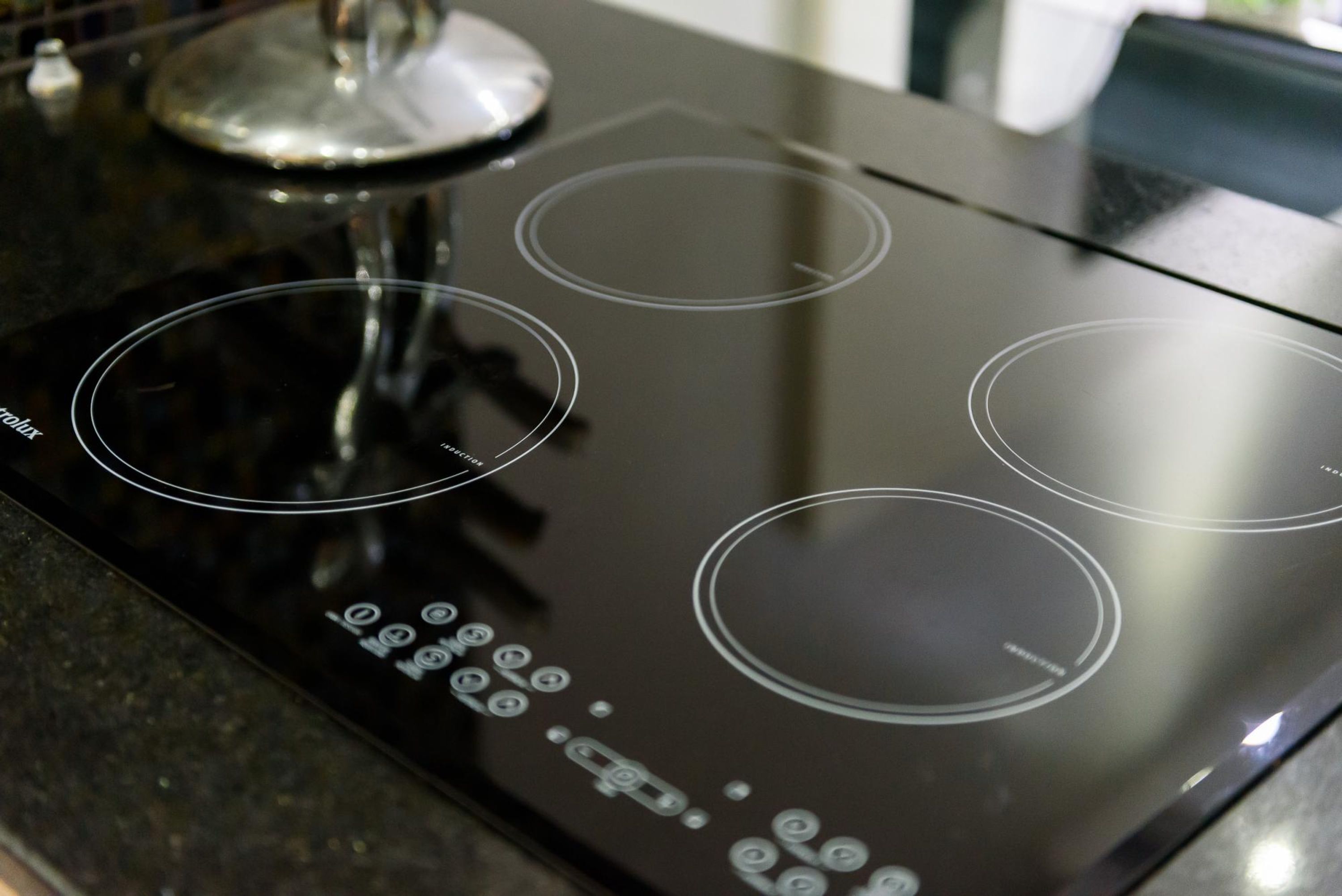 Une plaque de cuisson à induction noire, dotée de quatre zones de cuisson circulaires et d’un panneau de commande numérique.
