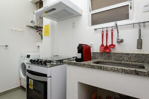 A compact kitchen with a built-in oven, a gas stove, a sink, and a window above the countertop.