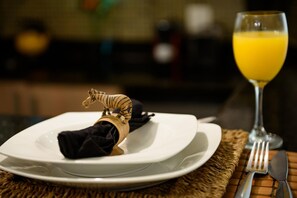 A dining table with a white plate, a napkin, a zebra napkin holder, a glass of orange juice, and cutlery. - 2 Minutes From Copacabana Beach Pf118 (Rio de Janeiro)
