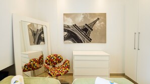 A room with a bed, a chair, a cabinet, and two paintings of the Eiffel Tower. - Style in Ipanema Good Location Vp305 (Rio de Janeiro)
