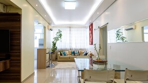 A modern living room with a sofa, a glass dining table, and chairs. There is a staircase on the left and a kitchen area in the background. - Style in Ipanema Good Location Vp305 (Rio de Janeiro)