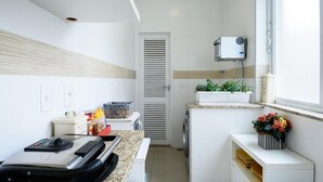 A compact kitchen with a built-in washing machine, a small window with a view, and a countertop with various items. - Style in Ipanema Good Location Vp305 (Rio de Janeiro)