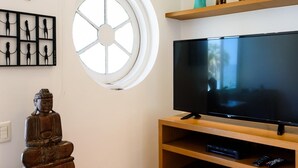 En stue med stort fladskærms-tv, tv-møbel i træ og en statue.