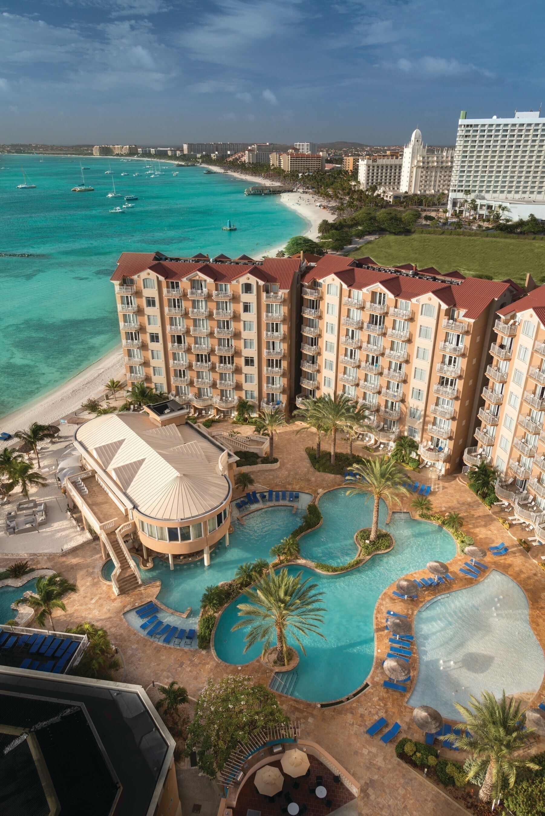 A hotel with a pool area, a beach, and ocean views.