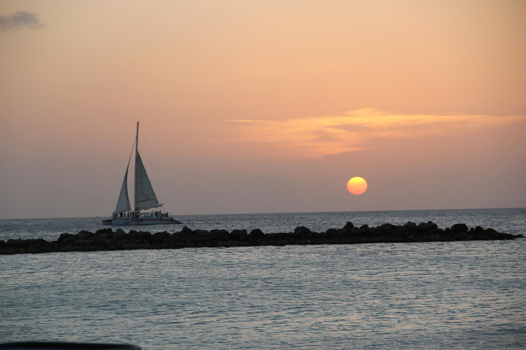 A sailboat on calm waters during sunset.