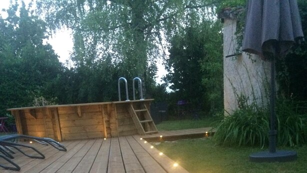 A wooden deck with a built-in bench and a small set of stairs leading up to a covered area.
