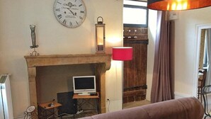 A living room with a fireplace, a television, a clock, and a red lamp.