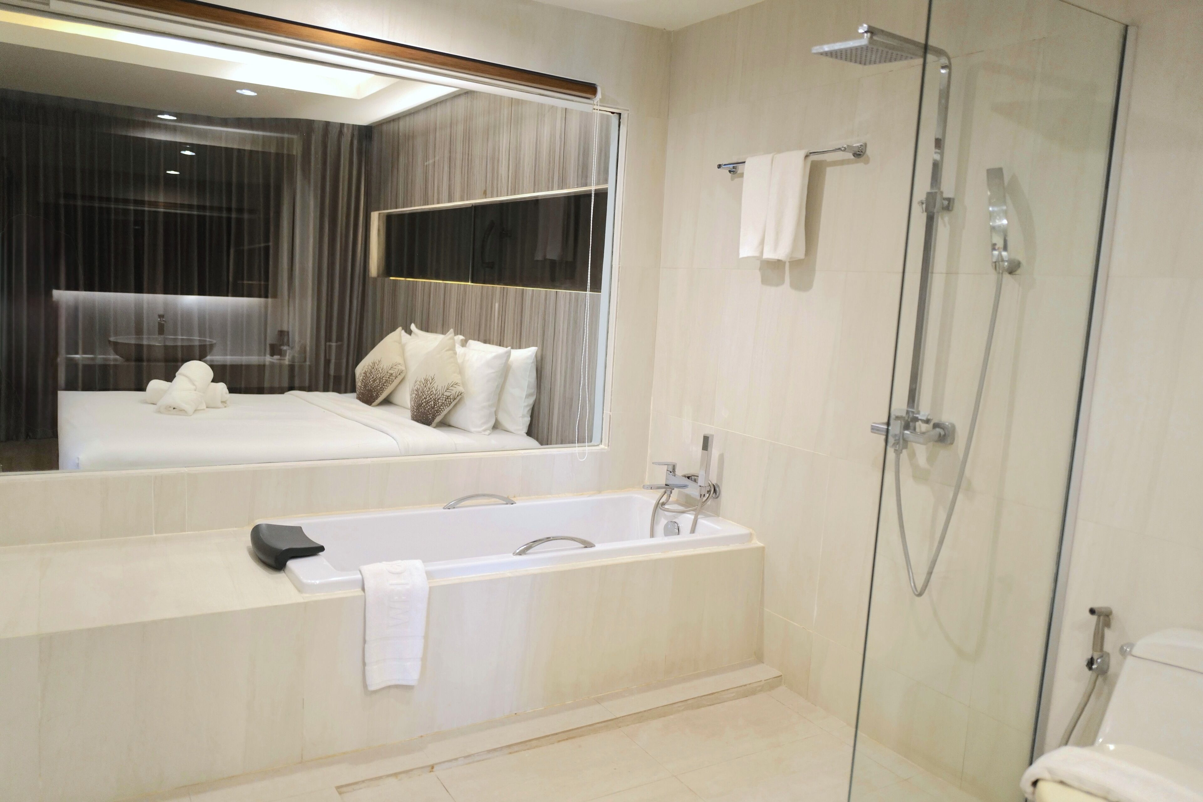 A modern bathroom with a bathtub, a glass-enclosed shower, and a large mirror.