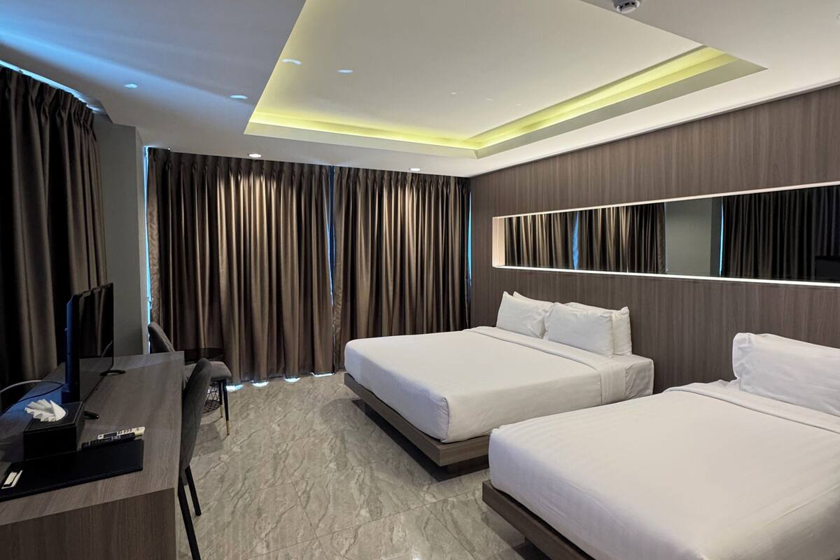 A modern hotel room with two beds, a desk, and a large mirror.