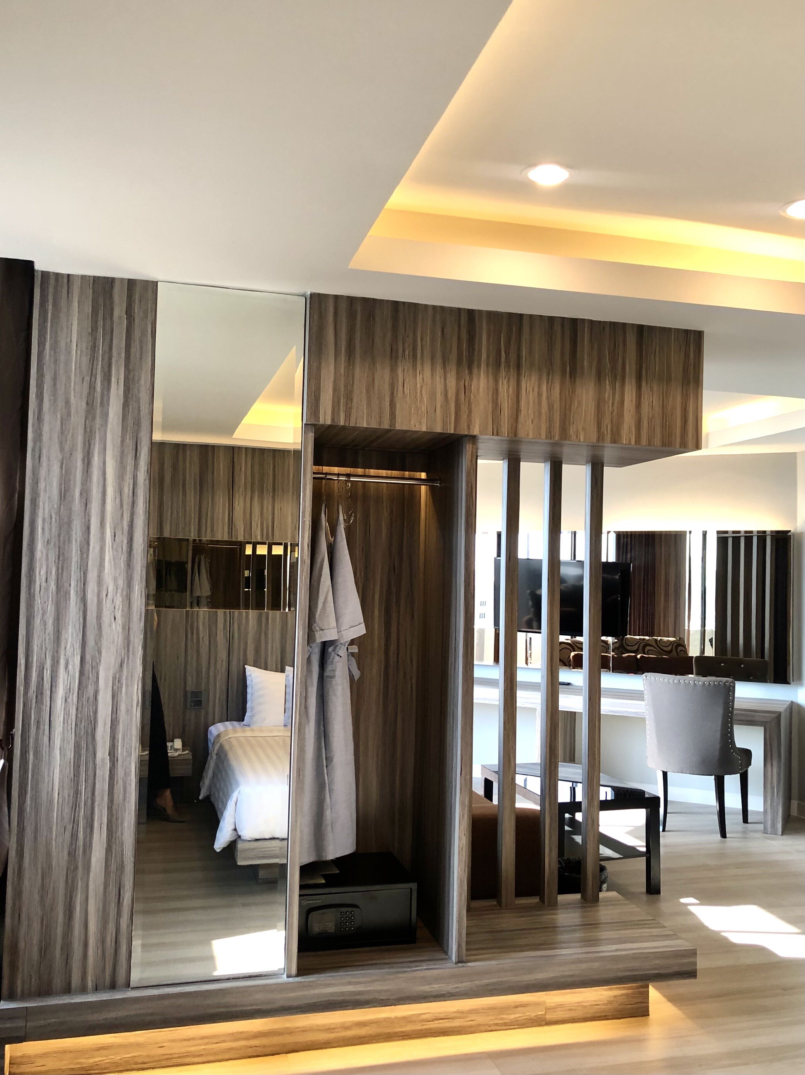 A modern hotel room with a large bed, a seating area with a table and chairs, and a view of the living area.