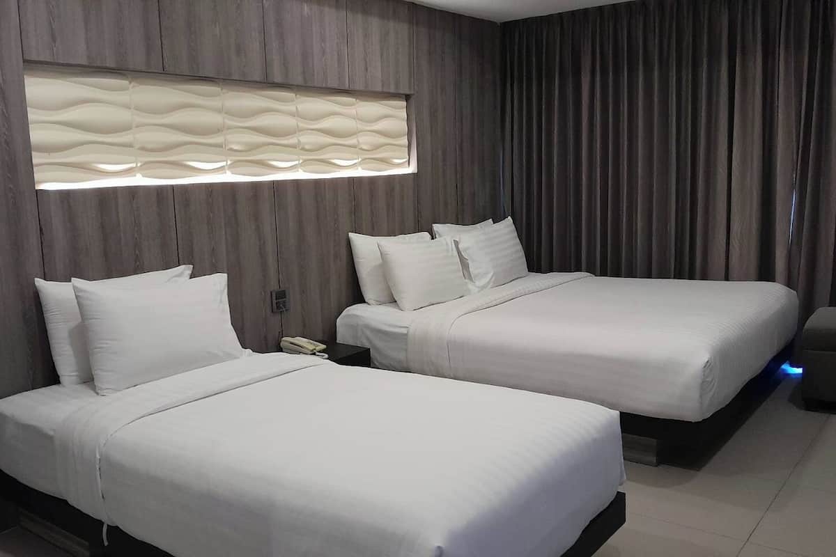 A hotel room with two beds, a modern light fixture, and a curtain.