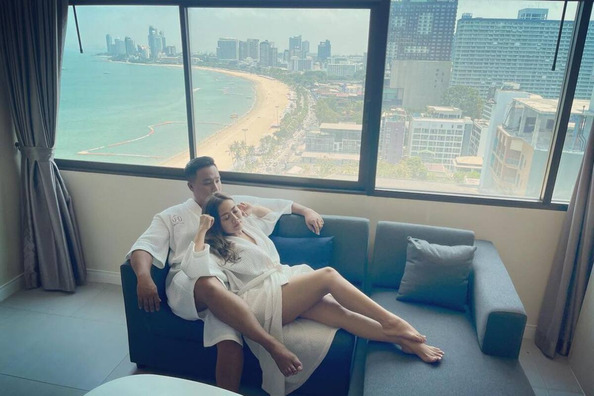 A modern living room with a large window overlooking a beach and cityscape.