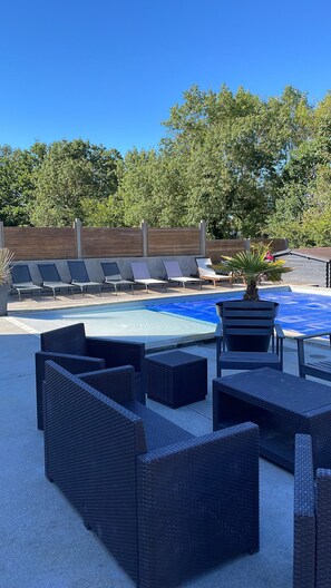 A pool area with lounge chairs and wicker furniture.