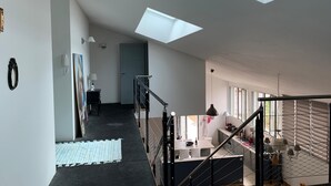 A modern apartment with a skylight, a staircase, a kitchen, and a living area.
