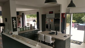 A modern kitchen with a central island, built-in appliances, and a dining area with white chairs.