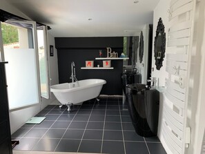 A modern bathroom with a freestanding bathtub, a black vanity, and a white sink.
