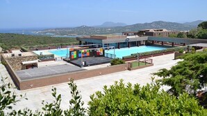 A rooftop pool area with a clear view of the sea and hills in the background.
