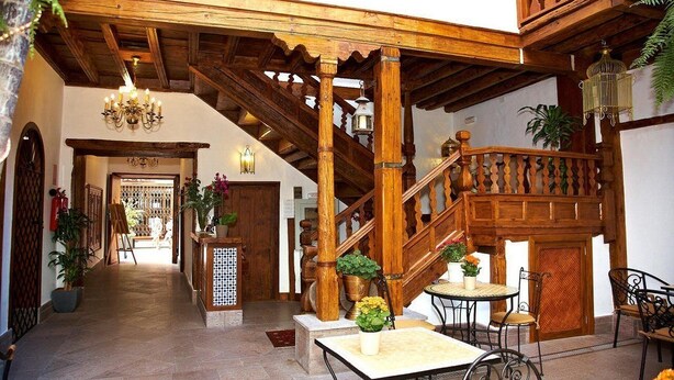 A wooden staircase with a railing, a chandelier, and potted plants. - Emblematico San Agustin Hotel (Icod de los Vinos)
