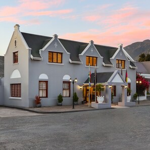 A two-story building with a reception area, multiple windows, and flags. - Premier Express Inn George (George)