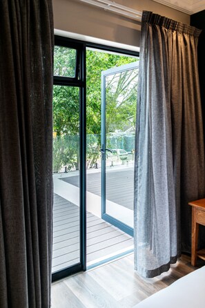 A room with a large sliding glass door leading to an outdoor area with a wooden deck and greenery. - Premier Express Inn George (George)