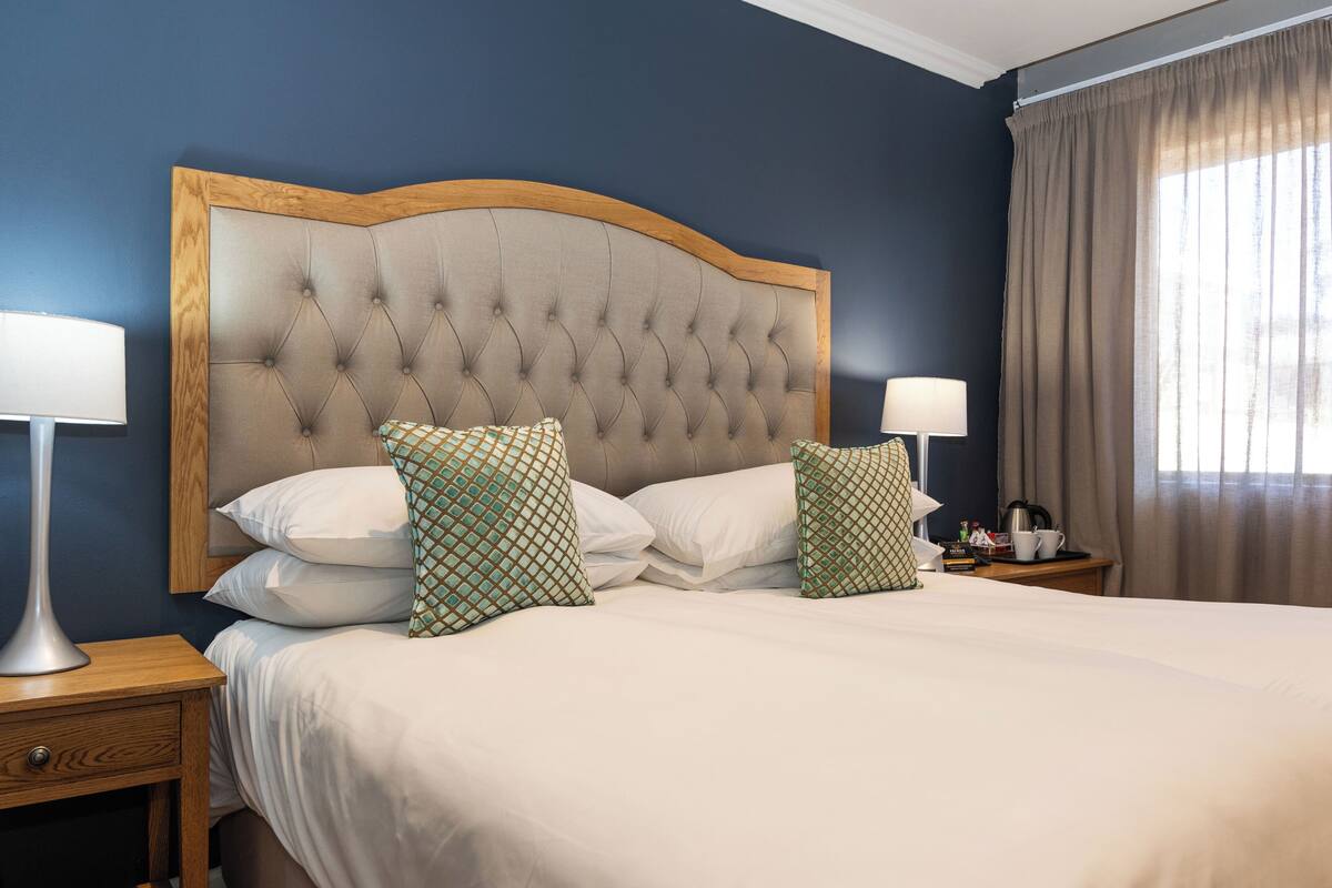 A neatly made bed with a tufted headboard, two bedside lamps, and patterned pillows.