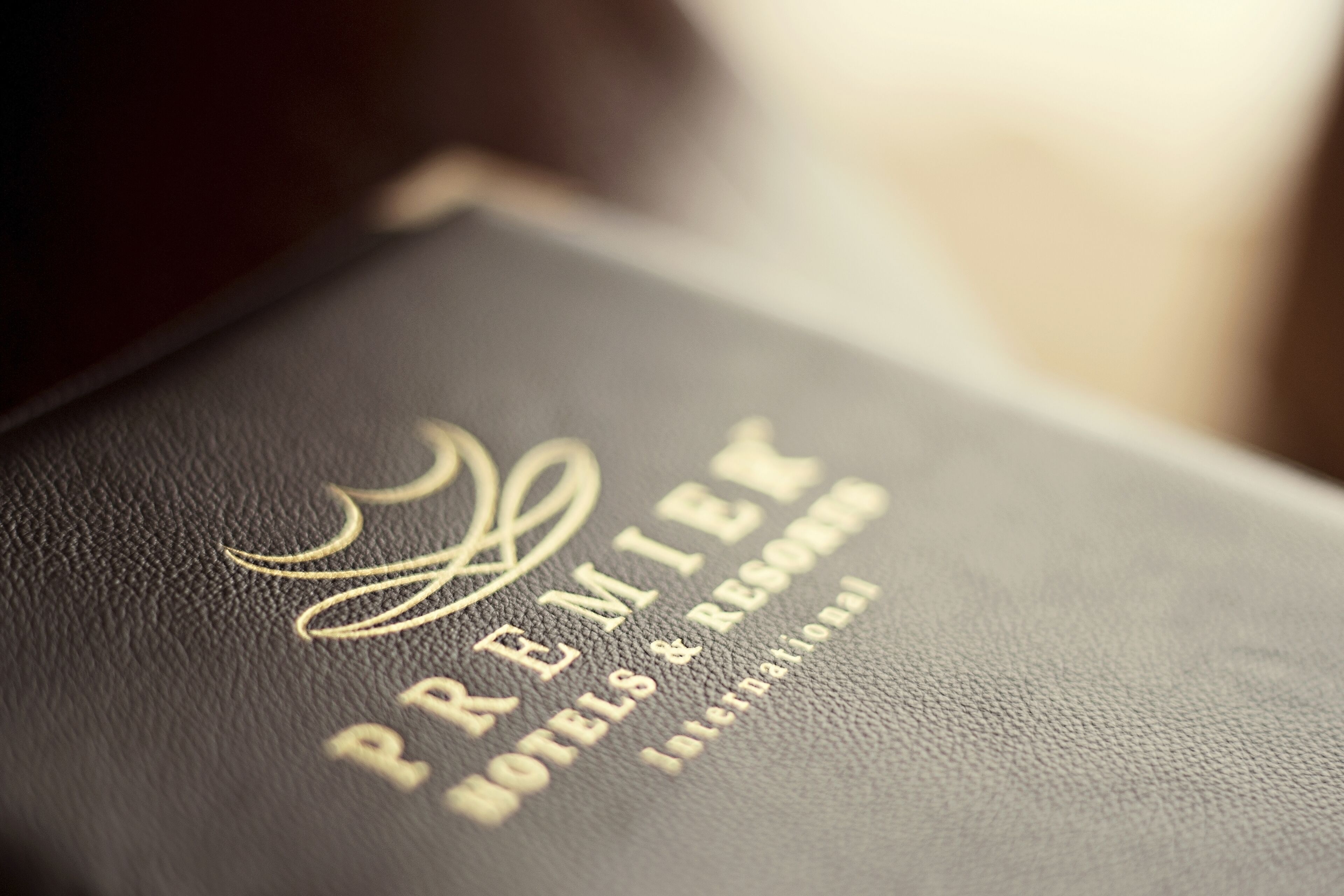 A black leather-bound book with embossed gold text reading "PREMIER HOTELS & RESORTS INTERNATIONAL."