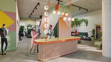 Ein modernes Interieur mit einem zentralen Tisch, der einen beleuchteten Spiegel präsentiert, umgeben von Sitzgelegenheiten und einer grünen Wand mit geometrischen Mustern.