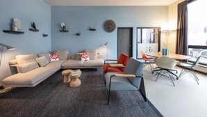 A modern living room with a sofa, chairs, a coffee table, and a dining area with a table and chairs. - ipartment Braunschweig @HOME by Best Western (Braunschweig)