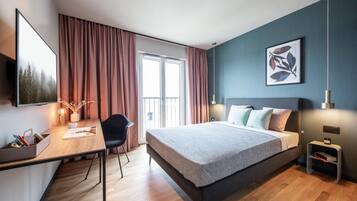 A modern bedroom with a bed, desk, chair, and artwork on the wall.