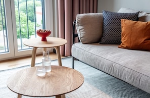 A modern living room with a sofa, a small round table, and a bowl of snacks. - ipartment Braunschweig @HOME by Best Western (Braunschweig)