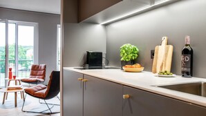 A modern kitchen with a built-in stove, a sink, and a countertop with a plant, cutting board, and wine bottle. - ipartment Braunschweig @HOME by Best Western (Braunschweig)