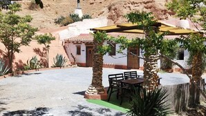 Un patio con una fuente de piedra, una pérgola y una zona de estar con mesa y sillas.